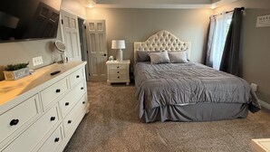 A bedroom with a bed, dresser, nightstand, lamp, and ceiling fan.