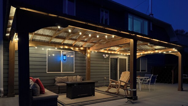 A covered outdoor patio with a wooden table, chairs, and a sofa.