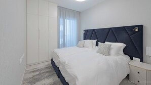 Une chambre à coucher moderne avec un grand lit, une armoire et une table de chevet.