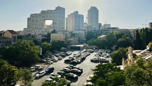 Un parking rempli de voitures, avec une vue sur la ville en arrière-plan.