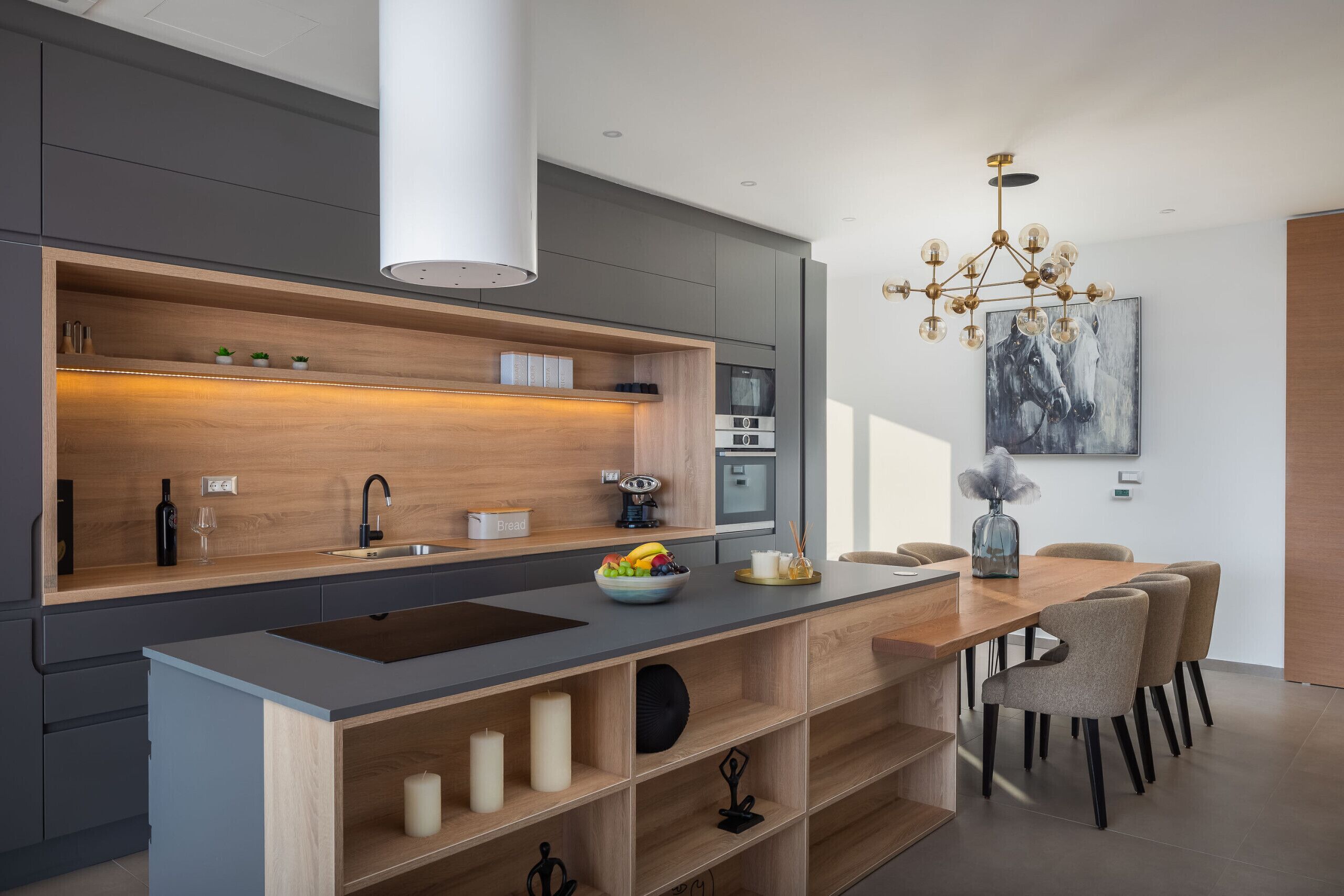 Een moderne keuken met een centraal eiland, ingebouwde apparatuur en een eethoek met stoelen.