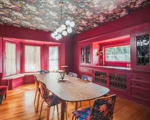 A dining area with a wooden table and chairs, a bench, and a window with a view.