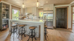 A spacious kitchen with a large island, stainless steel appliances, and bar stools.
