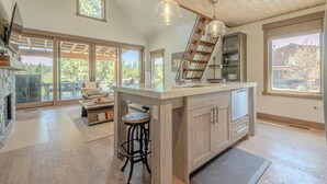 A spacious kitchen with a large island, wooden ceiling, and a view of the outdoors.