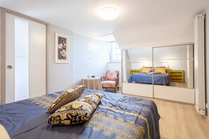 A bedroom with a bed, a chair, a small table, and a mirror. - Holiday Home 'Les Géraniums À 800m Plage' with Private Terrace, Shared Garden and Wi-Fi (Kerlaz)
