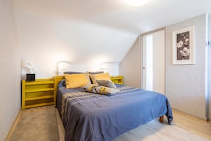 Ein Schlafzimmer mit Bett, Nachttischen, einer Wandlampe und einem gerahmten Bild.