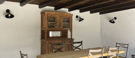 A dining area with a wooden table and chairs, a cabinet, and a ceiling with exposed beams.