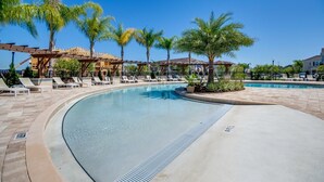 Un espace piscine avec des chaises longues et des palmiers.