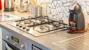 Una cocina con estufa a gas, cafetera y hervidor.