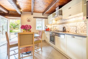 A kitchen with wooden beams, a clock, a stove, and a sink. - Holiday Home 'Penty À 800m De La Plage' with Private Terrace, Shared Garden and Wi-Fi (Kerlaz)