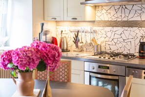A kitchen with a gas stove, oven, and various utensils. - Holiday Home 'Penty À 800m De La Plage' with Private Terrace, Shared Garden and Wi-Fi (Kerlaz)