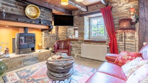 Un interior rústico con chimenea de piedra, sofá de cuero y televisión.