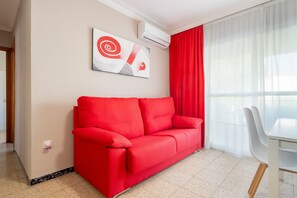 Un sofá rojo, una mesa blanca y un cuadro en la pared.