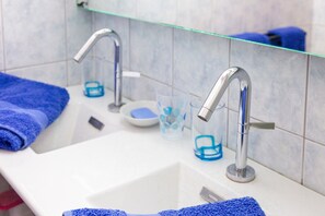 Ein Badezimmer mit zwei Waschbecken, einer Glasablage und einem blauen Handtuch.