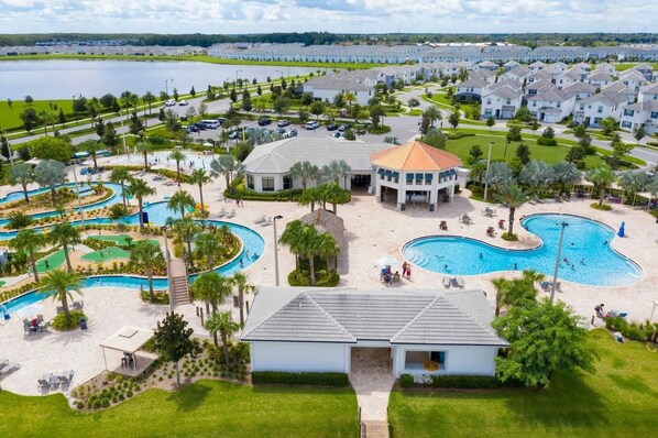 A resort with multiple swimming pools, a central building, and a view of a lake.