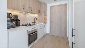 A compact kitchen with wooden cabinets, a built-in oven, a microwave, and a gas stove. - StayShort - Town Square Stylish Studio for 2 people! (Town Square)