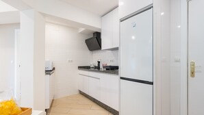 A modern kitchen with white cabinets, a black range hood, and a built-in oven.