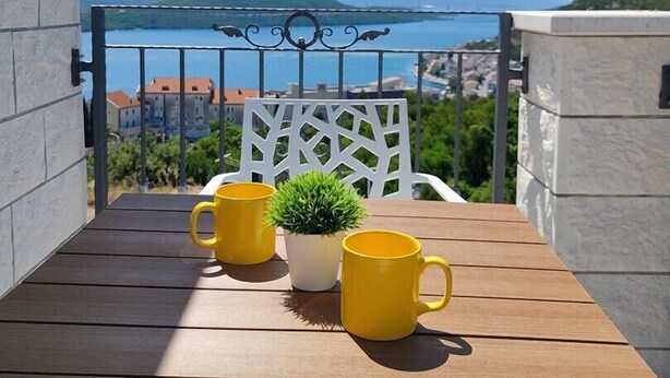 A balcony with a wooden table, two yellow mugs, and a potted plant. - Apartment with Sea and Nature view (Neum)