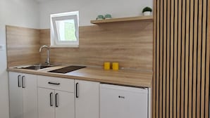 A modern kitchen with white cabinets, a wooden countertop, a built-in sink, and a window above the sink. - Apartment with Sea and Nature view (Neum)