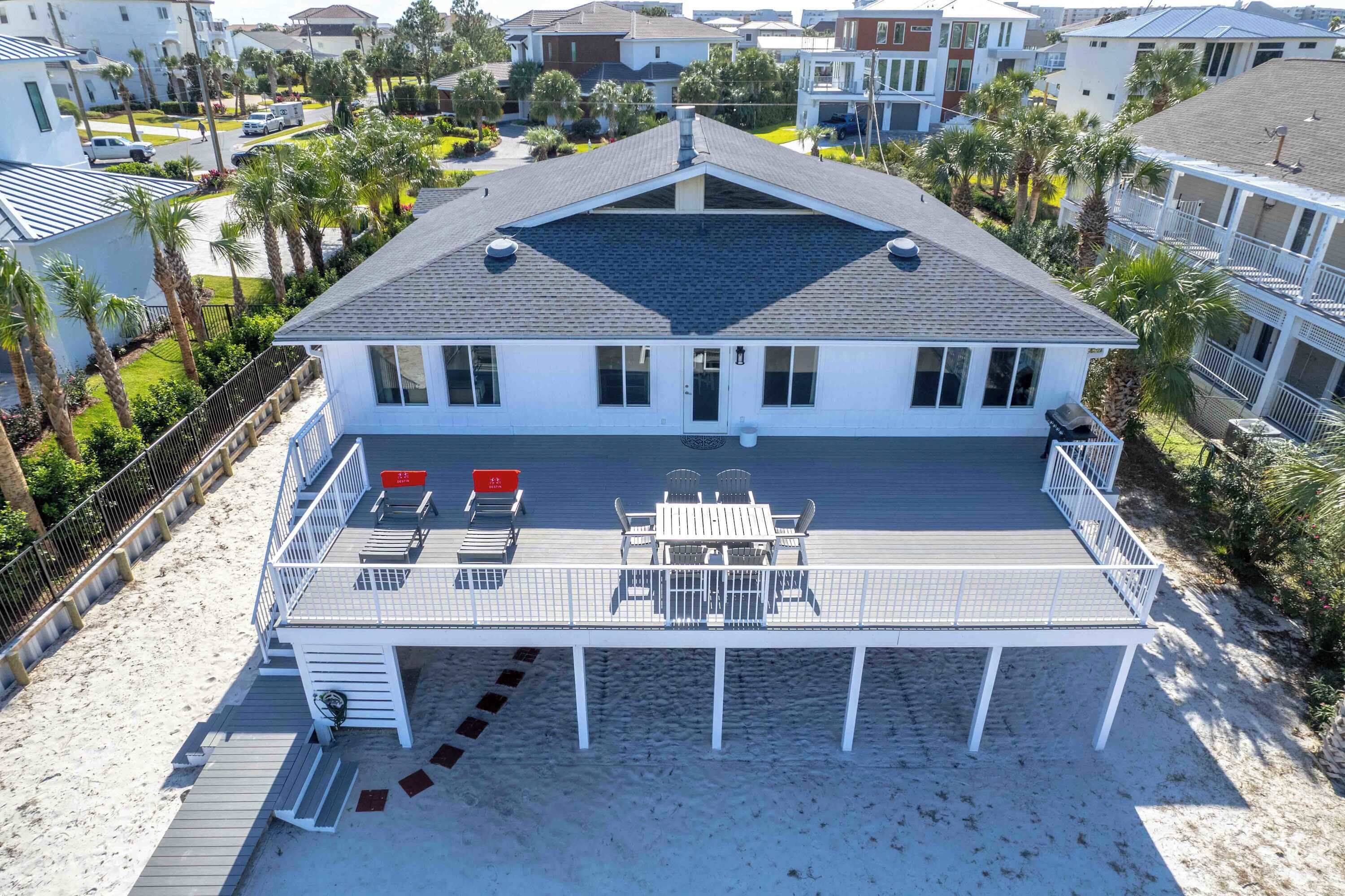 A two-story house with a covered patio, a pool, and a beach view.