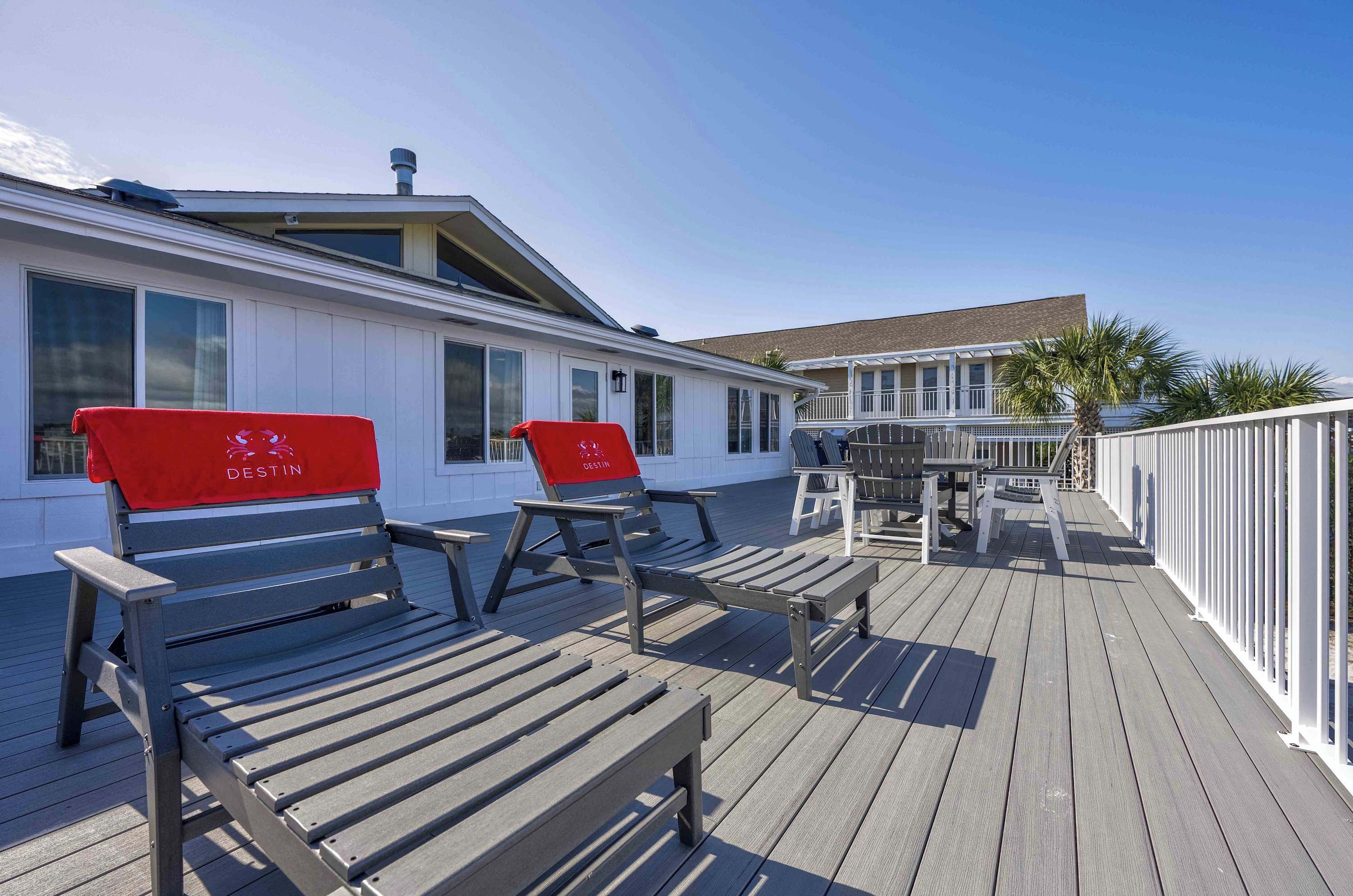 A wooden deck with two red chairs labeled "DESTIN" and a table with chairs.