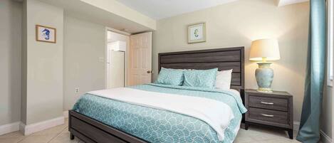 A bedroom with a bed, bedside table, lamp, and two framed pictures on the wall.