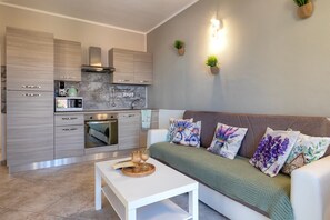 A modern kitchen with built-in appliances, a dining area with a white table, and a sofa with decorative pillows.
