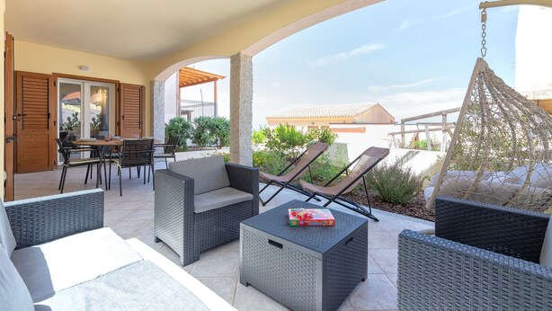 An outdoor patio with wicker furniture, a dining table, and chairs.