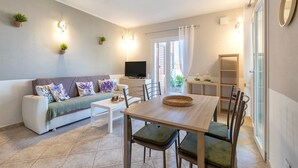 A modern living room with a sofa, TV, dining table, and chairs.