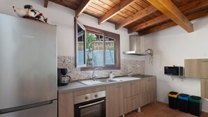 A modern kitchen with a stainless steel refrigerator, wooden cabinets, a built-in oven, a double sink, and a window with a view of the outside.