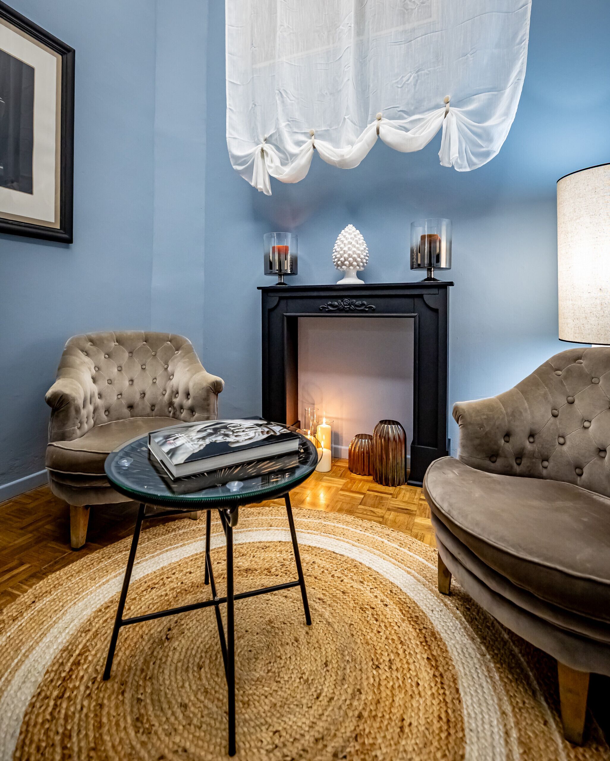 A living room with two armchairs, a glass coffee table, a fireplace, and a rug.
