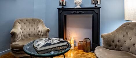 A living room with two armchairs, a glass coffee table, a fireplace, and a rug.