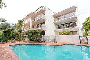 A modern multi-story building with balconies, a swimming pool, and surrounding greenery. - Lahaina 9 Beach Access 60 Seconds (Mooloolaba)