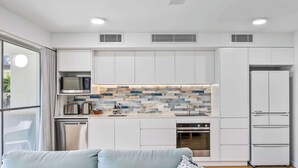 A modern kitchen with white cabinetry, a microwave, a kettle, and a built-in oven. - Lahaina 9 Beach Access 60 Seconds (Mooloolaba)