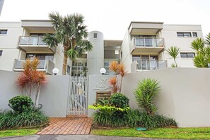 A modern building with a gated entrance, multiple balconies, and lush landscaping. - Lahaina 9 Beach Access 60 Seconds (Mooloolaba)