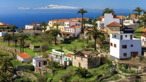 A coastal residential area with houses, palm trees, and a view of the sea. - Holiday Home 'Fagundo' with Mountain View, Private Terrace and Wi-Fi (Alajeró)