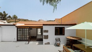 Une terrasse sur le toit avec une table et des chaises, une porte-fenêtre coulissante et une petite fenêtre.