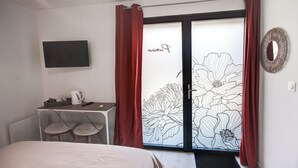Una habitación de hotel con una cama, un escritorio con una silla, una cafetera y una puerta con diseño floral.