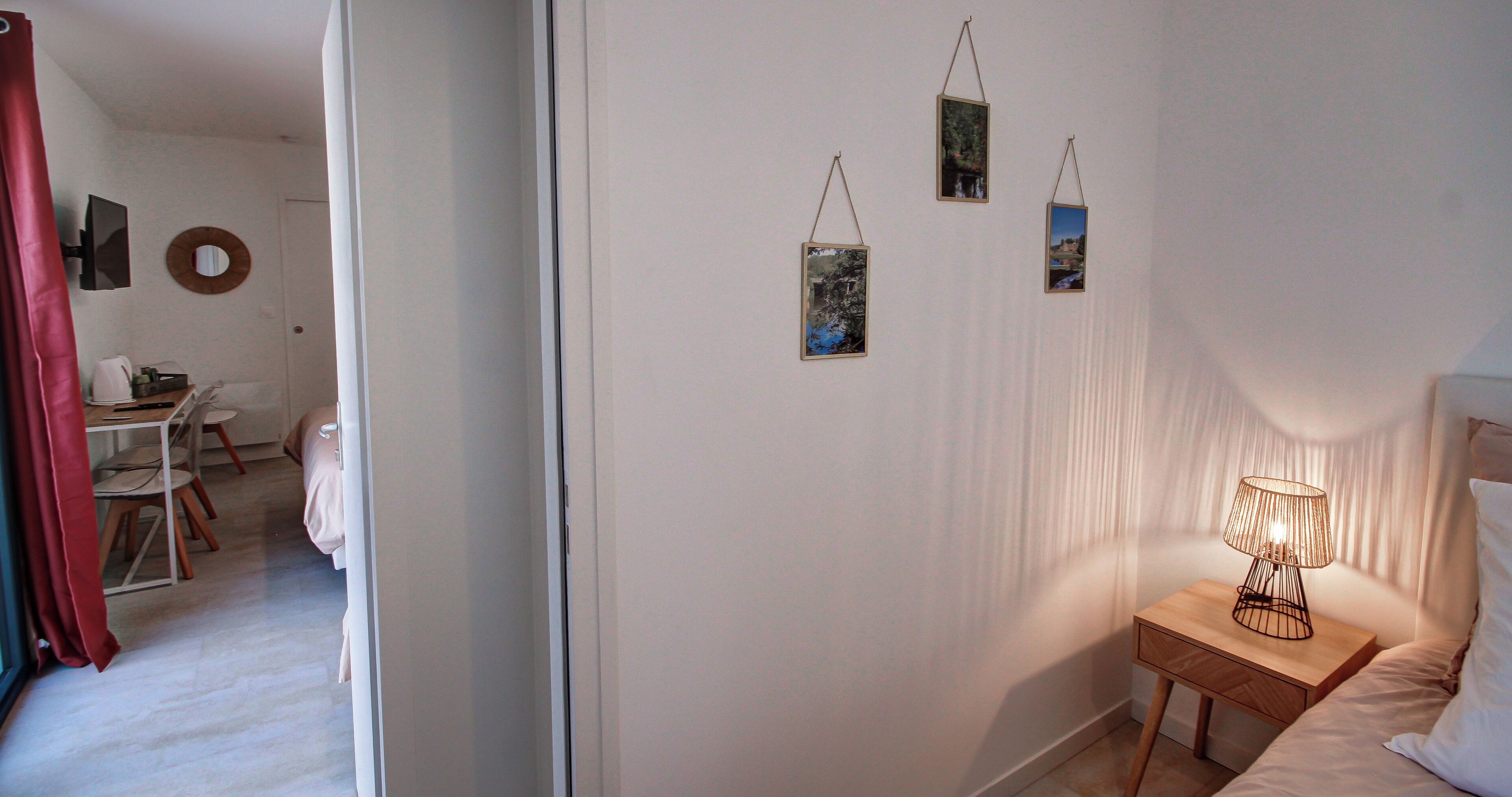 Un dormitorio con cama, mesita de noche, lámpara y tres cuadros en la pared.