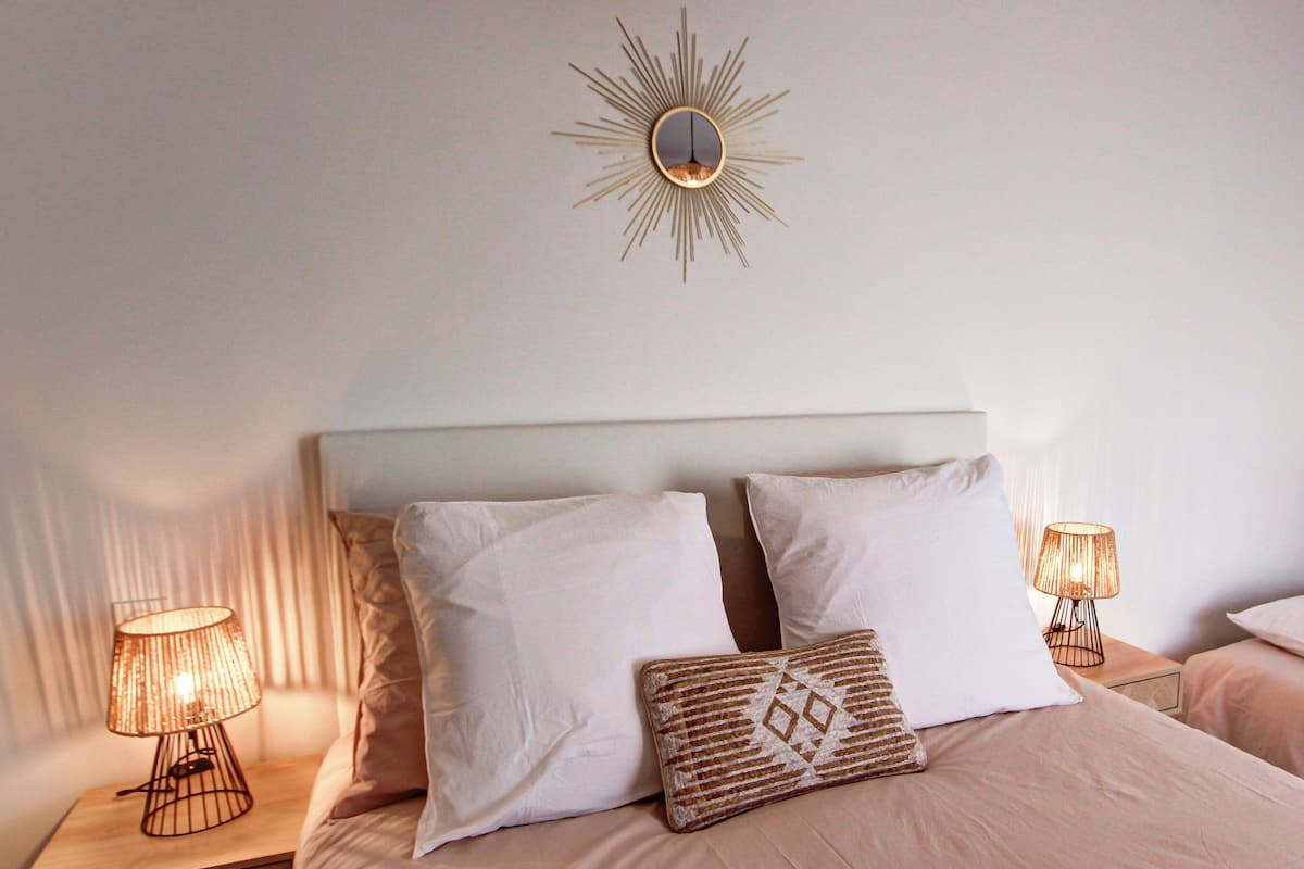 Ein Schlafzimmer mit zwei Betten, einer Wanduhr, Nachttischlampen und einem kleinen Regal.