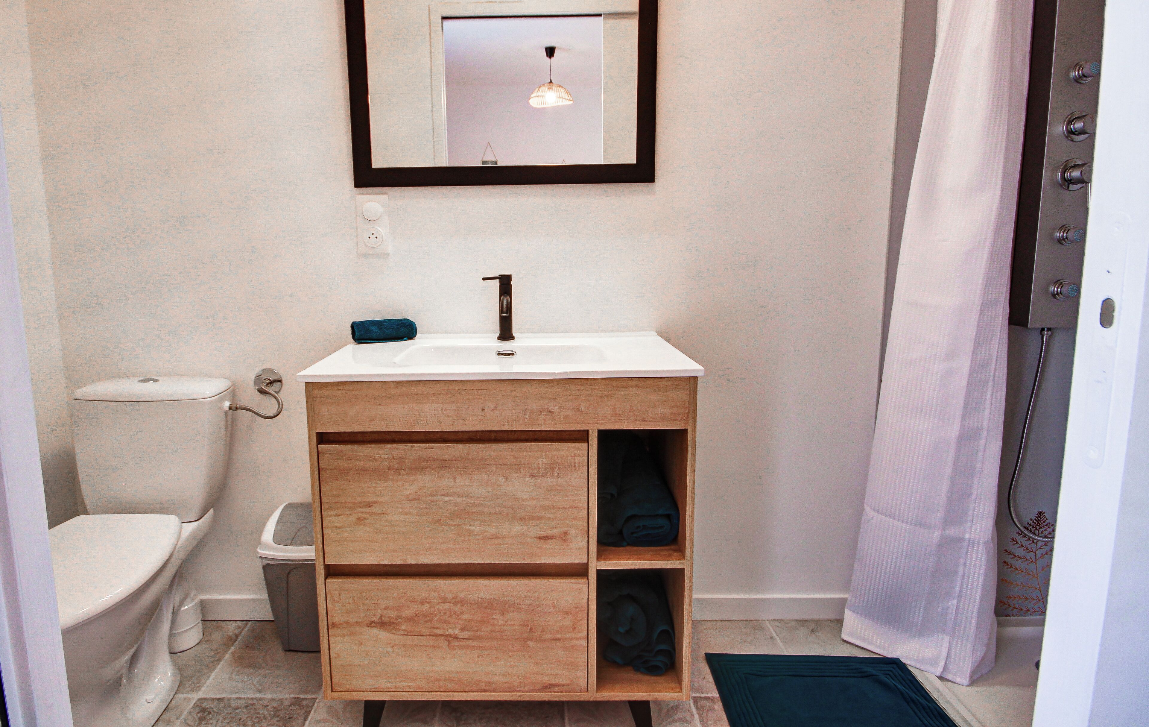 Ein Badezimmer mit einem weißen Waschbecken, einem Holz-Waschtisch und einem Spiegel darüber.