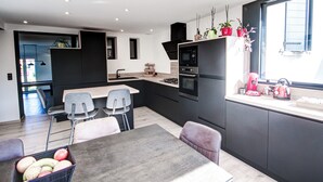 Una cocina moderna con comedor, que incluye una isla central, electrodomésticos integrados y una ventana con plantas.