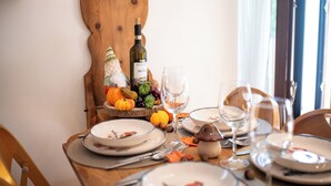 Una mesa de comedor dispuesta con platos, cubiertos, una botella de vino y adornos.
