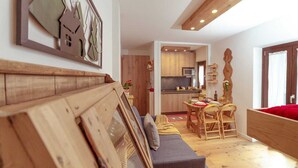 Una sala de estar acogedora con un banco de madera, un sofá gris y un comedor con una mesa y sillas de madera.