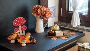 Una encimera de cocina con un florero de flores, una calabaza y setas decorativas.
