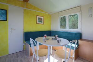Une pièce comprenant une table ronde, deux chaises, un banc, une porte et une fenêtre.