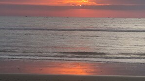 Une plage avec des vagues et un coucher de soleil.