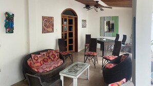 Un vaste espace de vie comprenant un canapé, des fauteuils, une table à manger et un ventilateur de plafond.