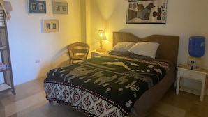 Une chambre à coucher comprenant un lit, une chaise, une table de chevet, une lampe et des éléments décoratifs sur les murs.