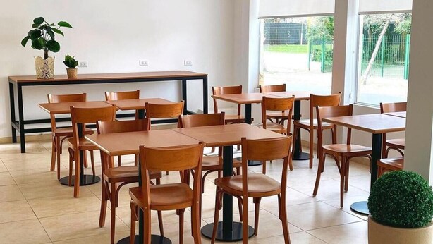 Zona interior àmplia amb diverses taules i cadires de fusta disposades de forma informal.